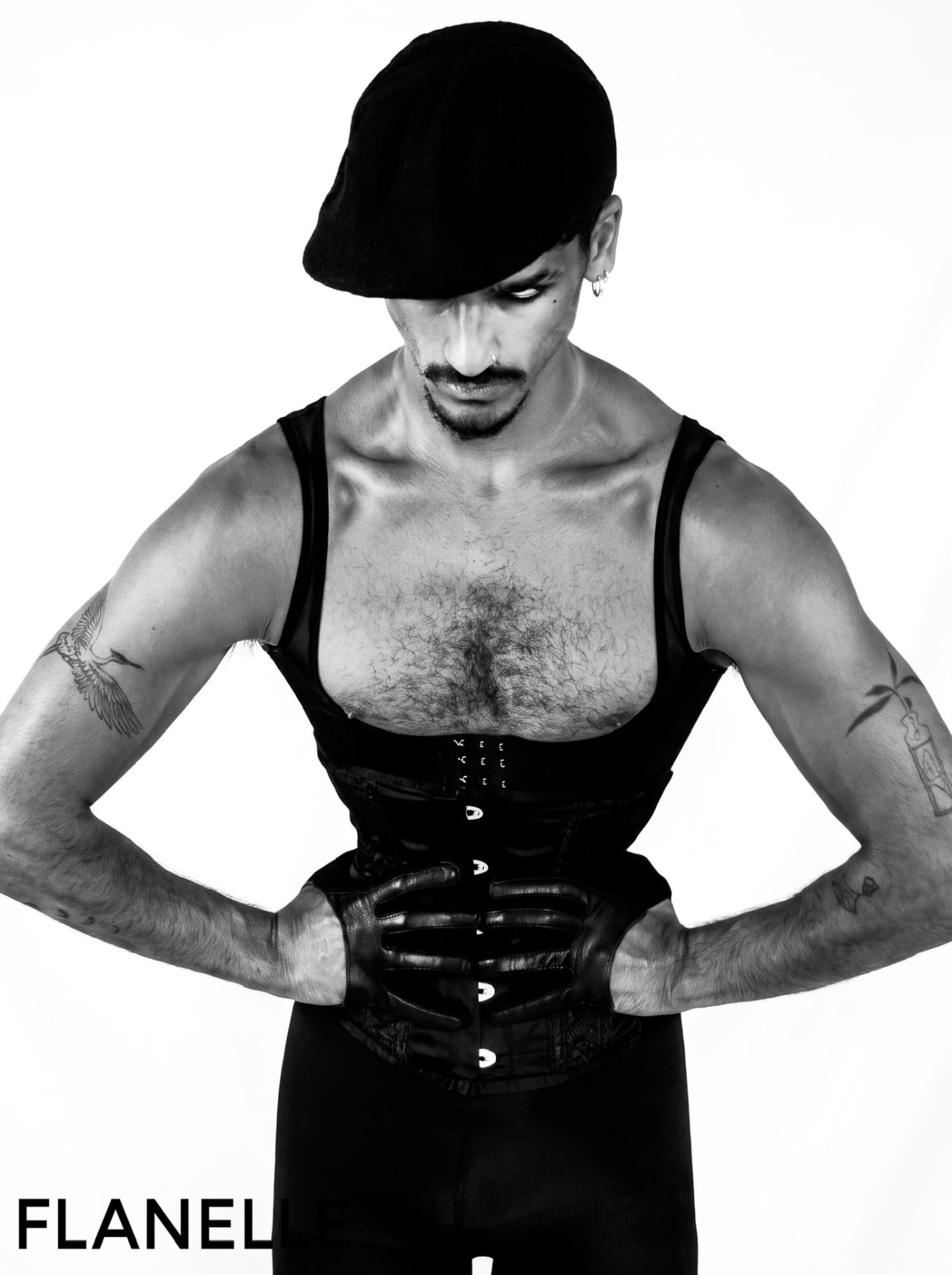 Figure in a leather corset and cap looking downward, leather gloves at the waist