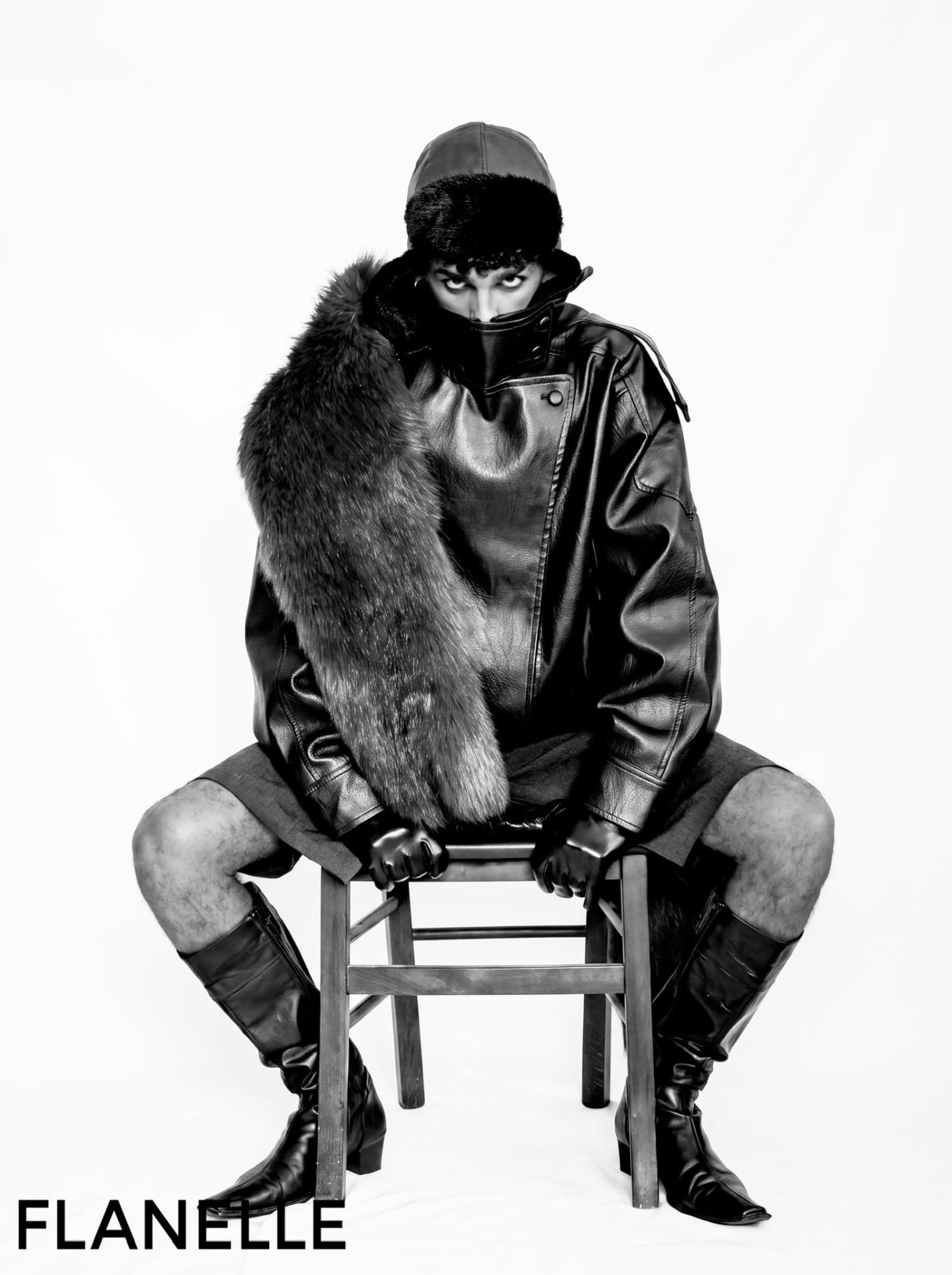 Seated figure in leather and fur, gaze fixed over the collar