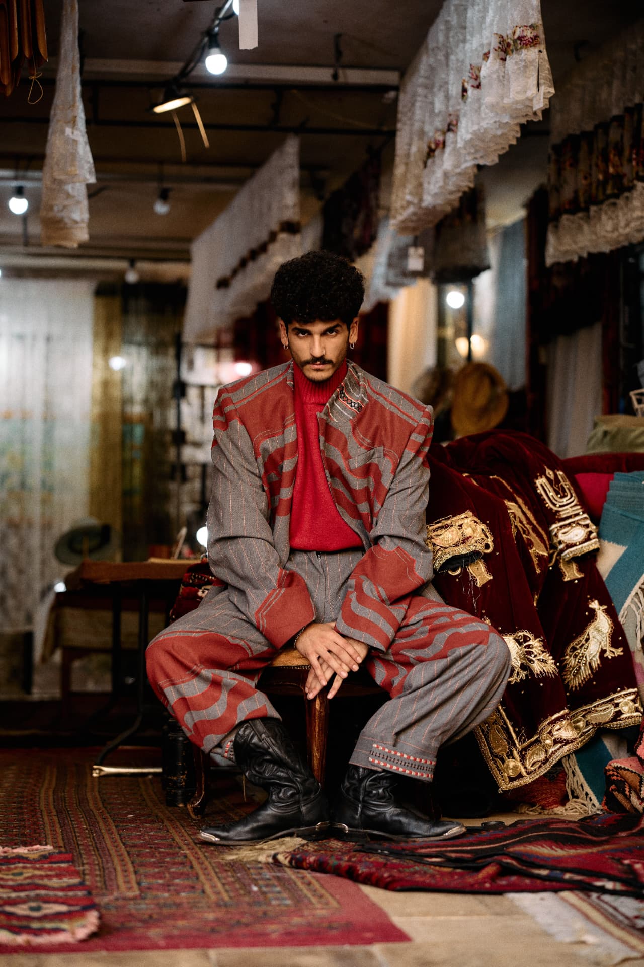 SELIN — model seated among carpets and textiles in a patterned suit