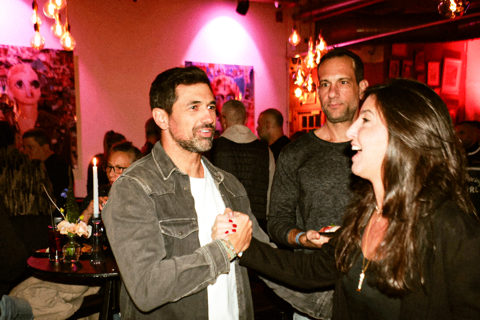Zohar Levkovitz's birthday — guests talking in candlelit pink light